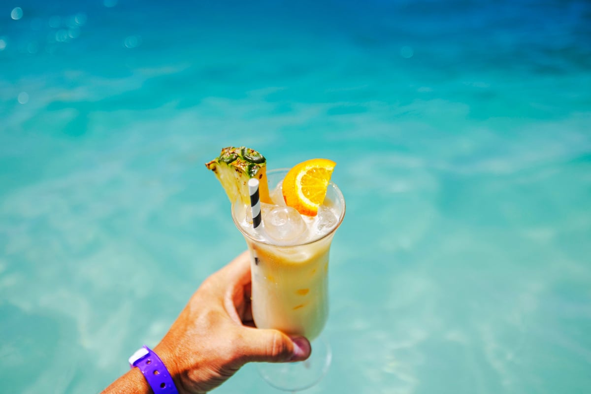Tropical cocktail with pineapple and orange garnish against turquoise waters