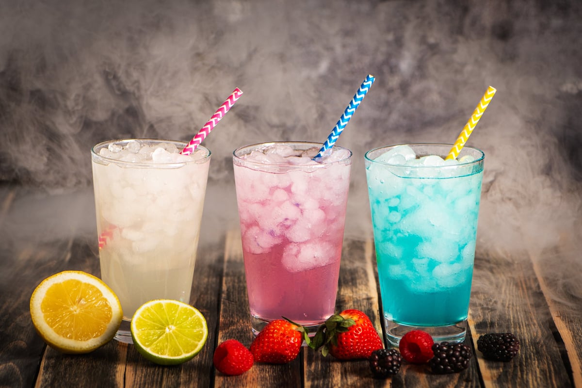Glasses with colorful soft drinks surrounded by various fruits