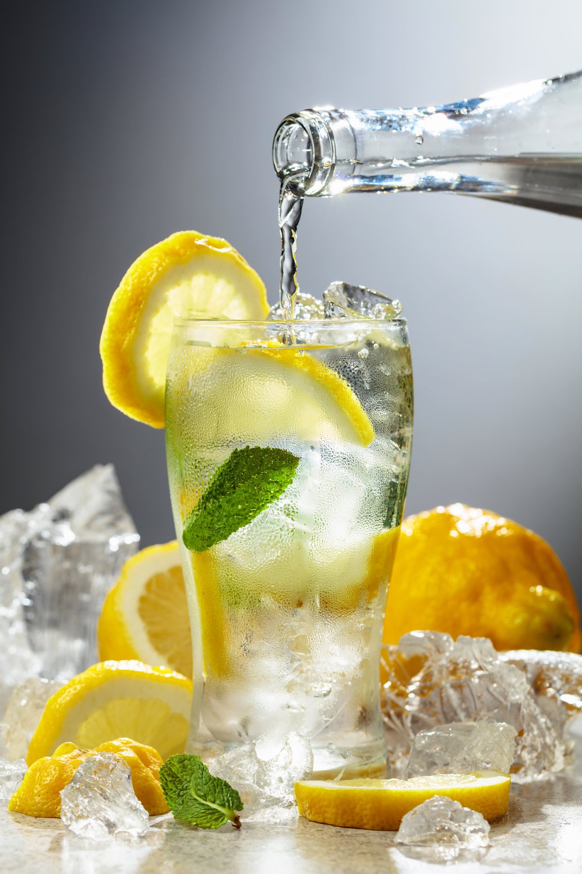 Transparent carbonated refreshing drink with fresh lemon, ice and mint